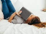 Kvinde læser i bog i sin seng